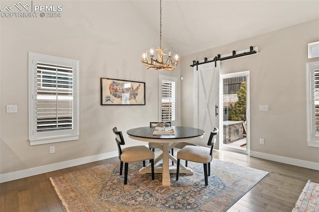 dining room with a barn door, hardwood / wood-style flooring, and an inviting chandelier