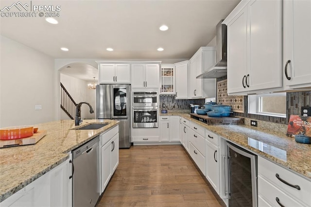 kitchen with stainless steel appliances, white cabinetry, and beverage cooler