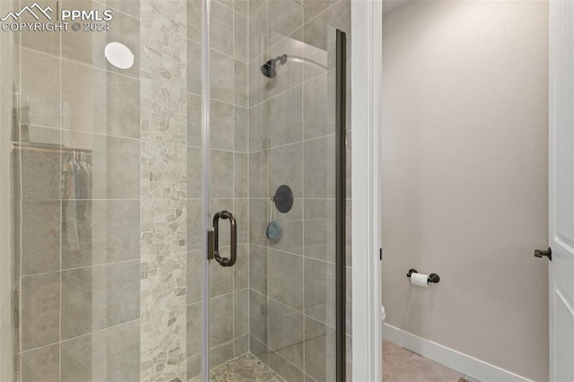 bathroom featuring a shower with shower door and toilet