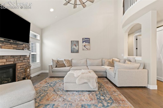 living room with ceiling fan, a fireplace, high vaulted ceiling, and wood-type flooring