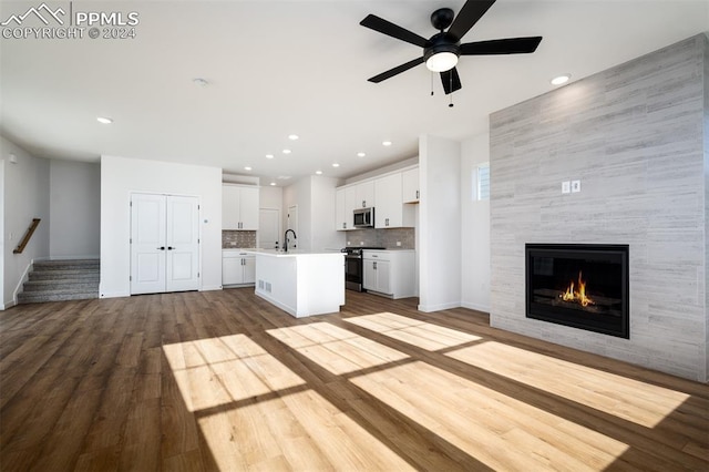 unfurnished living room featuring a fireplace, ceiling fan, sink, and light hardwood / wood-style flooring