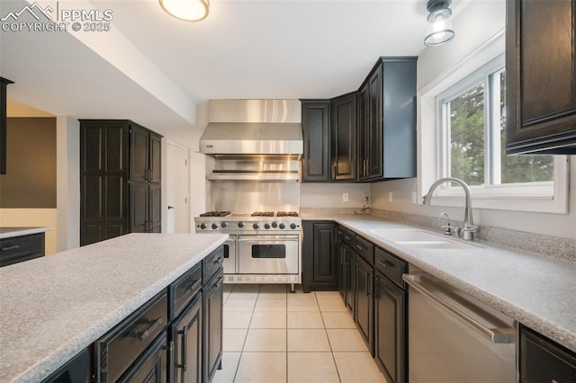 kitchen with sink, wall chimney exhaust hood, stainless steel appliances, and light tile patterned floors