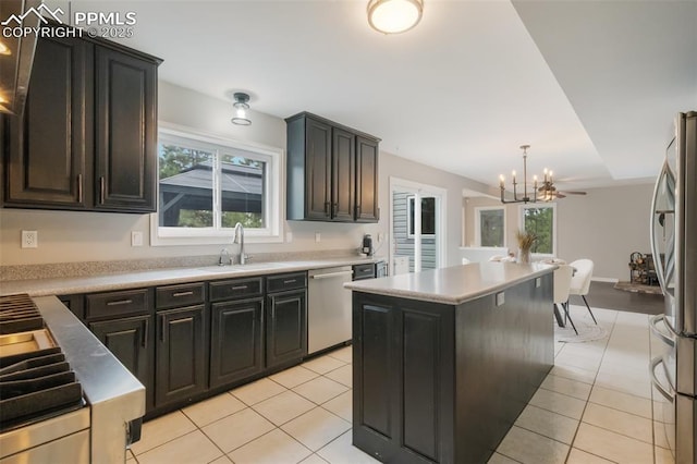 kitchen featuring appliances with stainless steel finishes, sink, decorative light fixtures, a kitchen island, and light tile patterned flooring