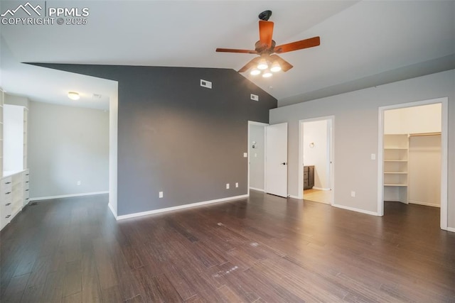 unfurnished bedroom with ensuite bath, ceiling fan, dark wood-type flooring, vaulted ceiling, and a walk in closet