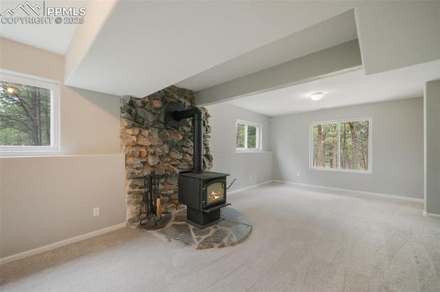 unfurnished living room featuring beam ceiling, a wood stove, and carpet floors