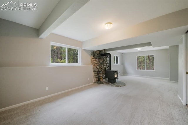 unfurnished living room with beam ceiling, a wood stove, and light carpet