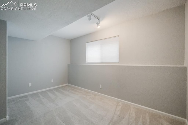 carpeted spare room with a textured ceiling and rail lighting