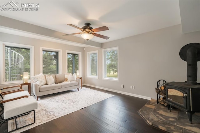 living room with a wood stove, ceiling fan, and dark hardwood / wood-style flooring