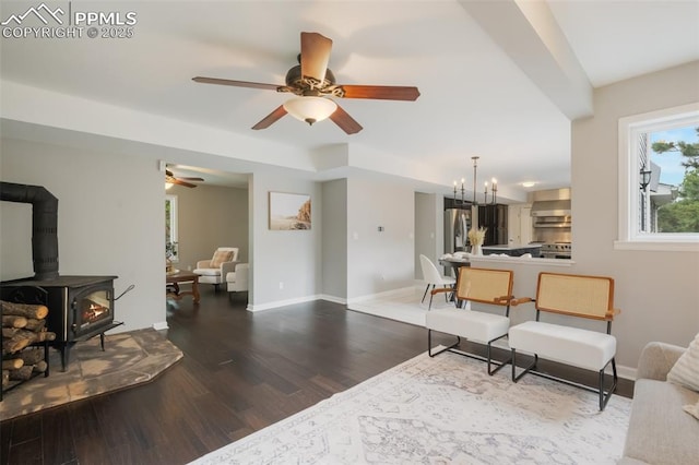 living room with hardwood / wood-style flooring, ceiling fan with notable chandelier, and a wood stove