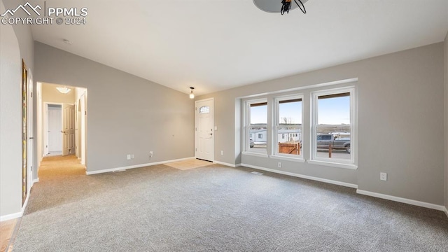 carpeted spare room with lofted ceiling