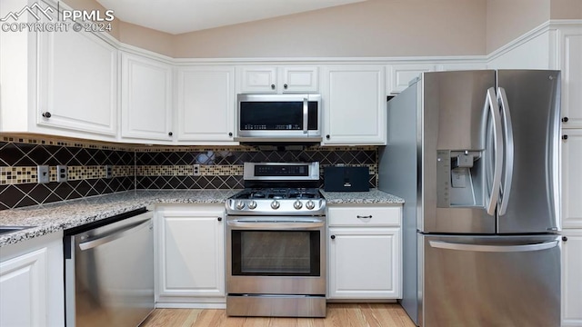 kitchen with light stone countertops, white cabinets, and stainless steel appliances