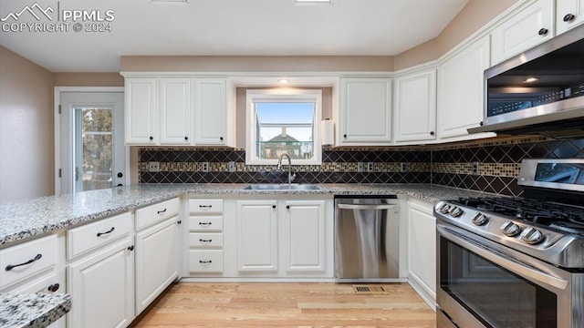 kitchen with light stone countertops, white cabinetry, sink, and appliances with stainless steel finishes