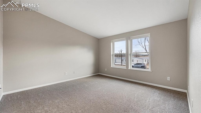 carpeted spare room with vaulted ceiling