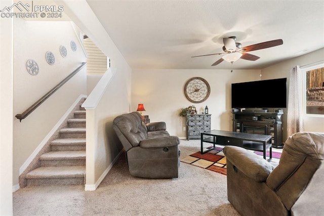 living room featuring carpet, ceiling fan, and a fireplace