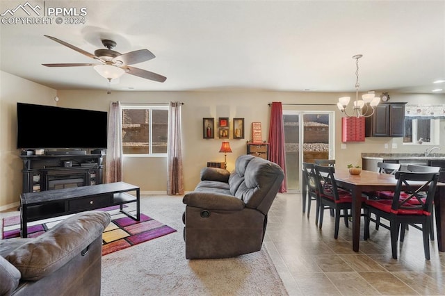 living room featuring plenty of natural light, ceiling fan with notable chandelier, and sink