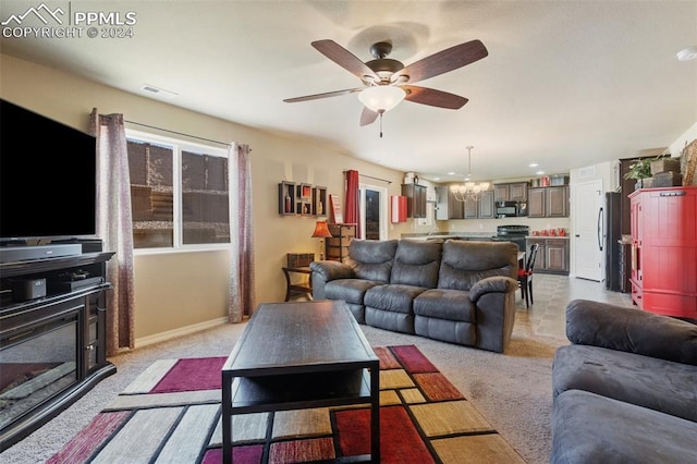 carpeted living room featuring ceiling fan with notable chandelier