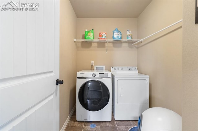 laundry room featuring washer and clothes dryer and dark tile patterned flooring