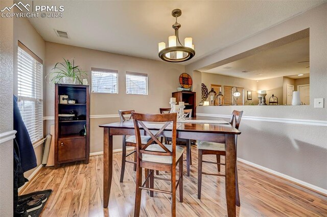 dining room with light hardwood / wood-style floors and an inviting chandelier