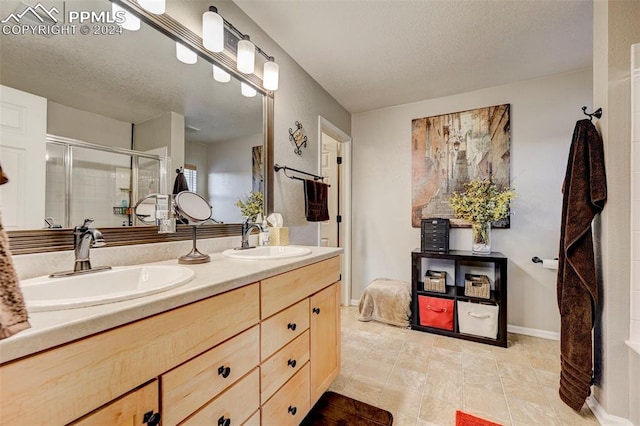 bathroom with tile patterned floors, a shower with door, vanity, and a textured ceiling