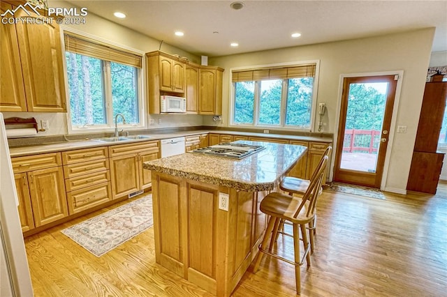 kitchen with a center island, a healthy amount of sunlight, white appliances, and sink