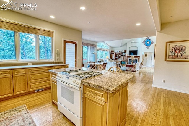 kitchen with light stone counters, light hardwood / wood-style flooring, white range, pendant lighting, and a kitchen island