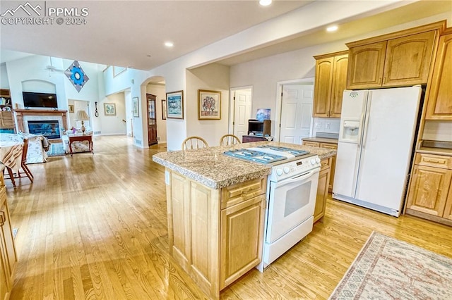 kitchen featuring a kitchen island, light stone countertops, white appliances, and light hardwood / wood-style flooring