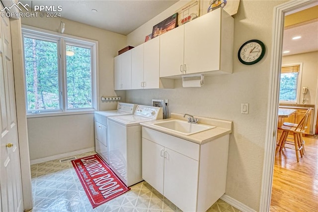 laundry area with washing machine and clothes dryer, cabinets, sink, and a healthy amount of sunlight