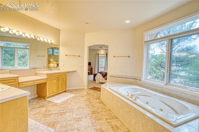 bathroom featuring vanity, a relaxing tiled tub, a wealth of natural light, and ceiling fan