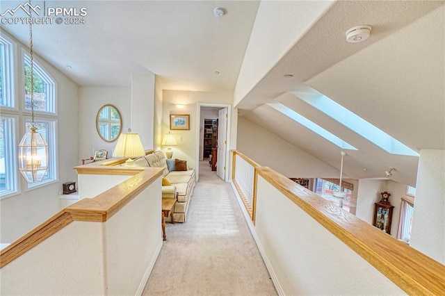 hallway featuring light carpet and lofted ceiling with skylight