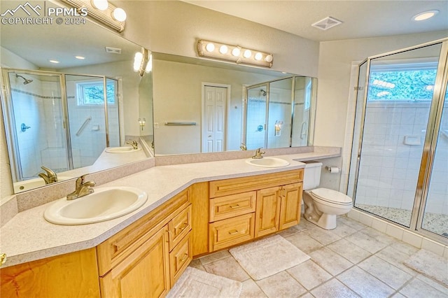 bathroom featuring tile patterned flooring, vanity, toilet, and a shower with door