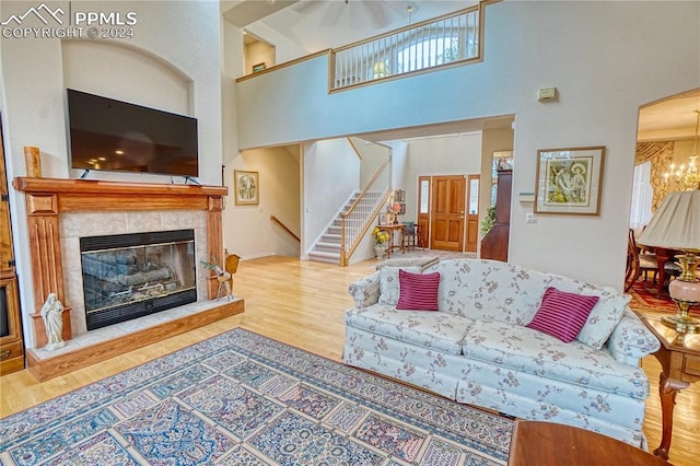 living room with a fireplace, hardwood / wood-style floors, a high ceiling, and an inviting chandelier