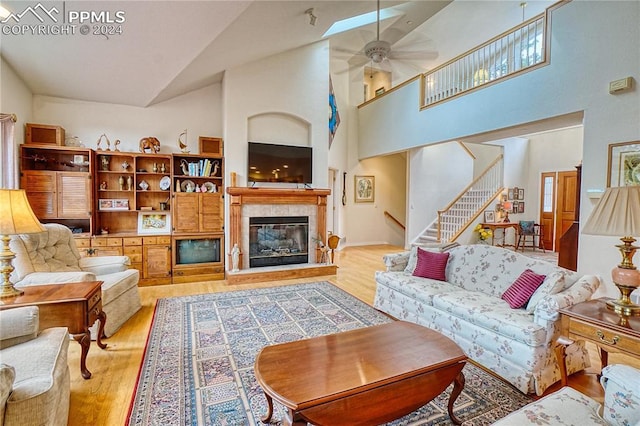 living room with a fireplace, high vaulted ceiling, light hardwood / wood-style flooring, and ceiling fan