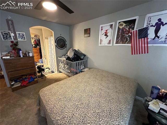 carpeted bedroom featuring ceiling fan, a walk in closet, and a closet