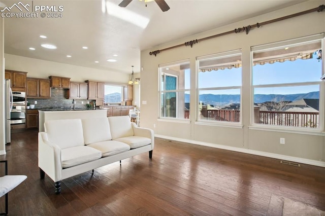 living room featuring a mountain view, ceiling fan, and dark wood-type flooring