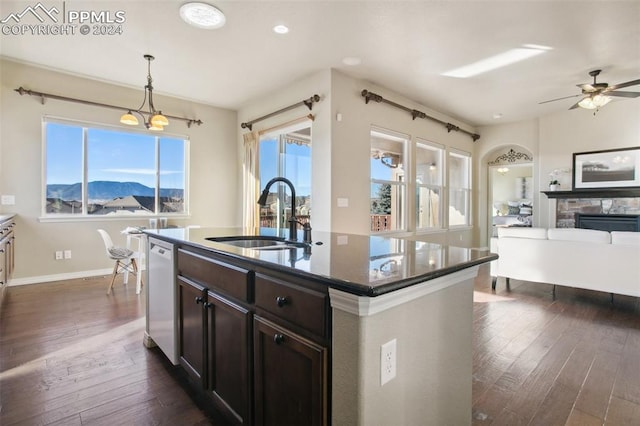 kitchen with dishwashing machine, a kitchen island with sink, dark wood-type flooring, sink, and a mountain view