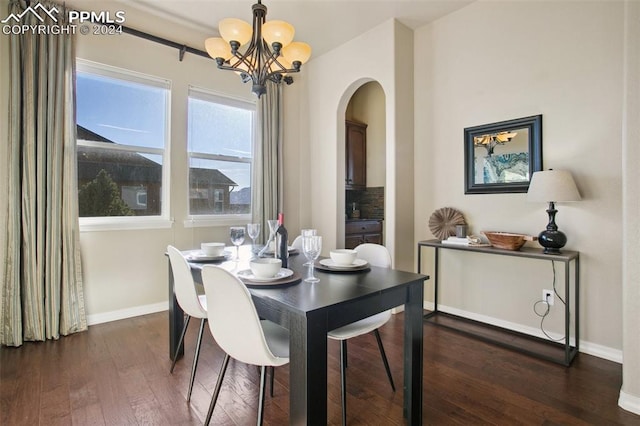 dining room with dark wood-type flooring and an inviting chandelier