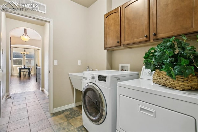 clothes washing area with cabinets, washer and dryer, light wood-type flooring, and a notable chandelier