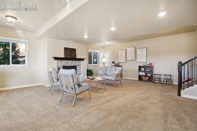 carpeted living room with a stone fireplace