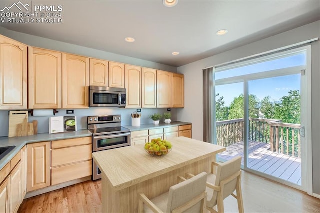 kitchen with light wood-type flooring, light brown cabinets, a center island, and stainless steel appliances