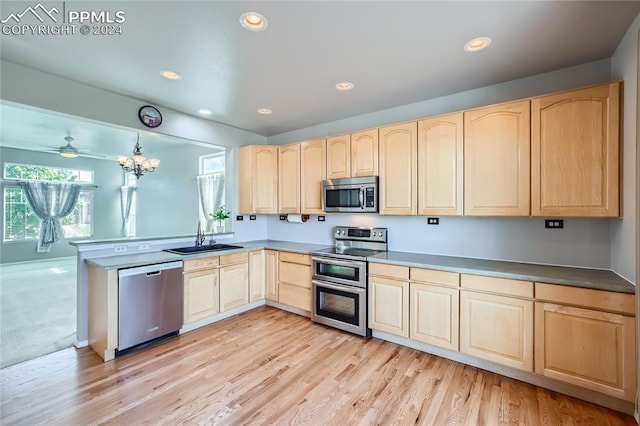 kitchen with light brown cabinets, stainless steel appliances, hanging light fixtures, and sink