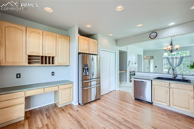 kitchen featuring pendant lighting, light brown cabinets, sink, stainless steel appliances, and a chandelier