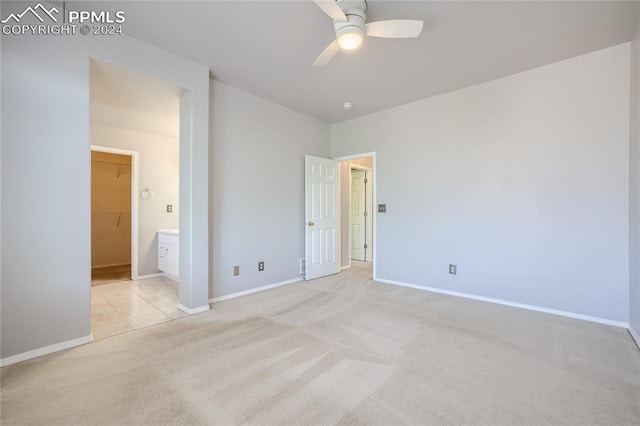 unfurnished bedroom featuring ceiling fan, a walk in closet, light carpet, and a closet