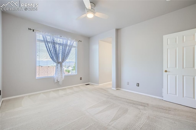 spare room with ceiling fan and light carpet