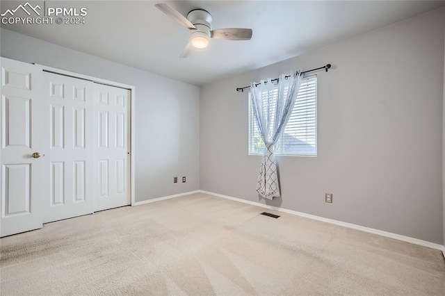 unfurnished bedroom with ceiling fan, a closet, and light carpet