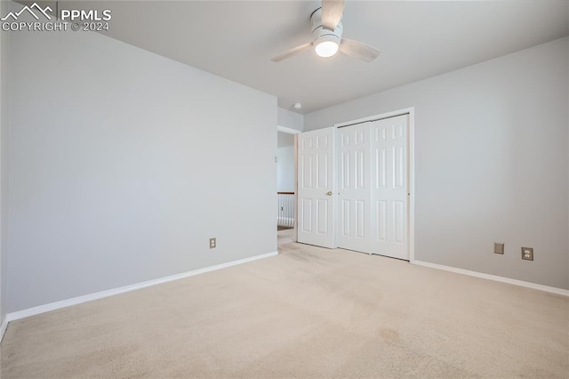 unfurnished bedroom with ceiling fan, light colored carpet, and a closet