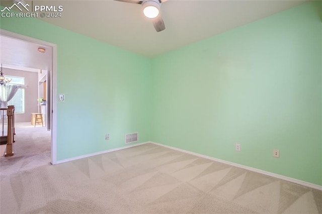 unfurnished room featuring light carpet and ceiling fan with notable chandelier