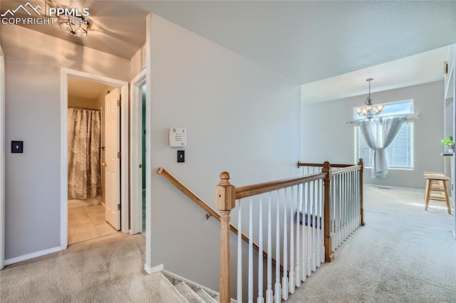 hall featuring light colored carpet and a chandelier