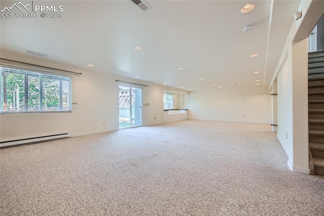 unfurnished living room with light carpet, a wealth of natural light, and a baseboard heating unit