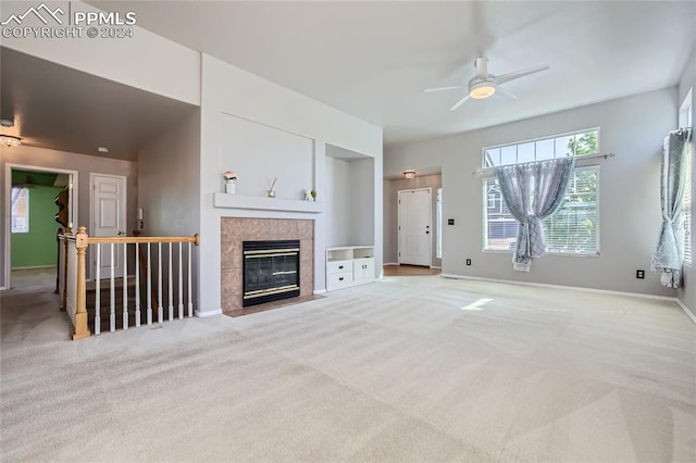 unfurnished living room featuring a fireplace, light carpet, and ceiling fan