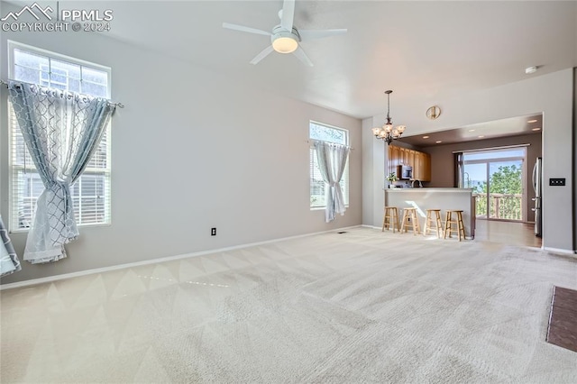 unfurnished living room featuring light carpet and ceiling fan with notable chandelier